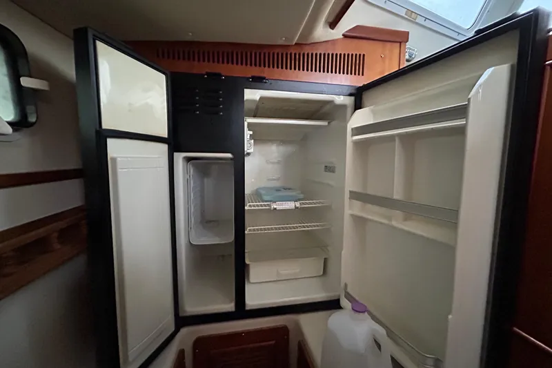 Slide: The Image of Open refrigerator inside 2004 PDQ 34 Power Catamaran, showcasing storage shelves and compartments. - 17