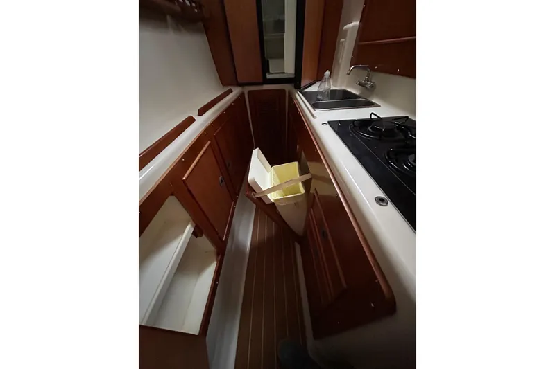 Slide: The Image of 2004 PDQ 34 Power Catamaran kitchen with stove, sink, and wooden cabinetry. - 20