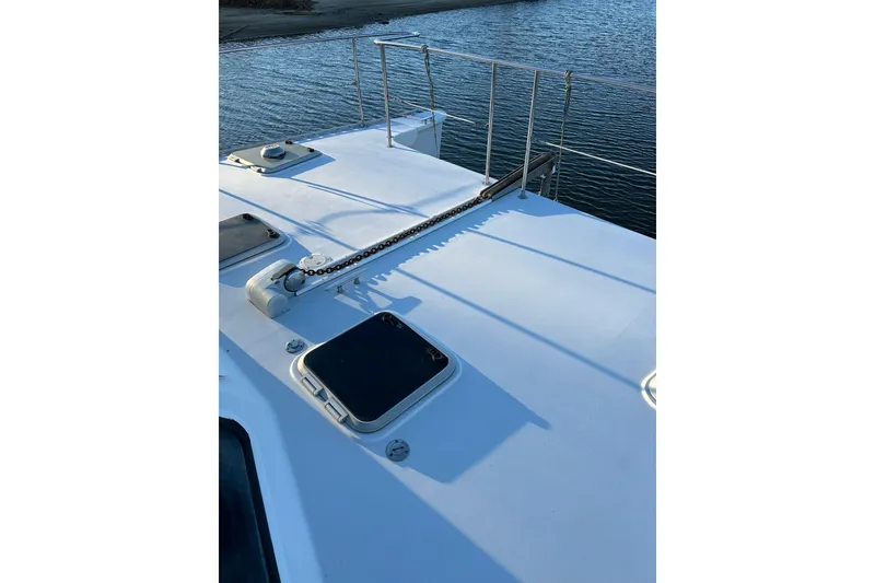 Slide: The Image of 2004 PDQ 34 Power Catamaran deck with hatches and railing by the water. - 8
