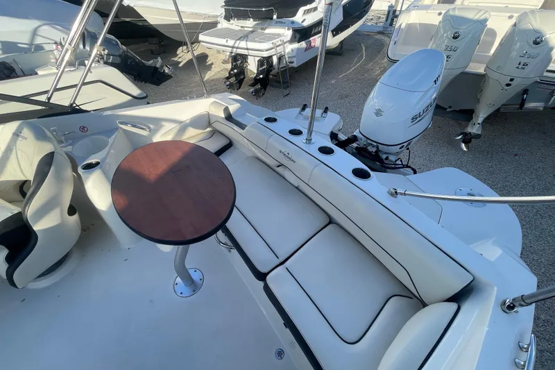 Slide: The Image of 2021 Stingray 201 DC boat interior with seating, table, and Suzuki outboard motor. - 28