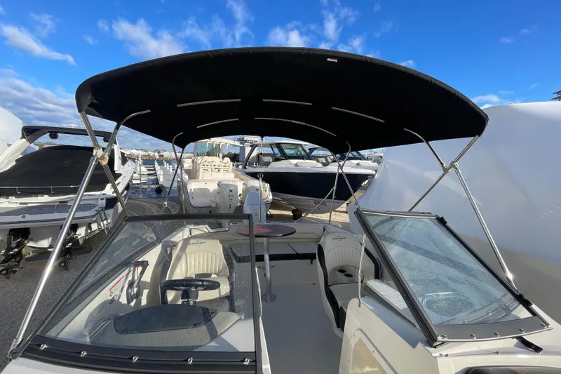 Slide: The Image of 2021 Stingray 201 DC boat with canopy, docked under a clear blue sky. - 32