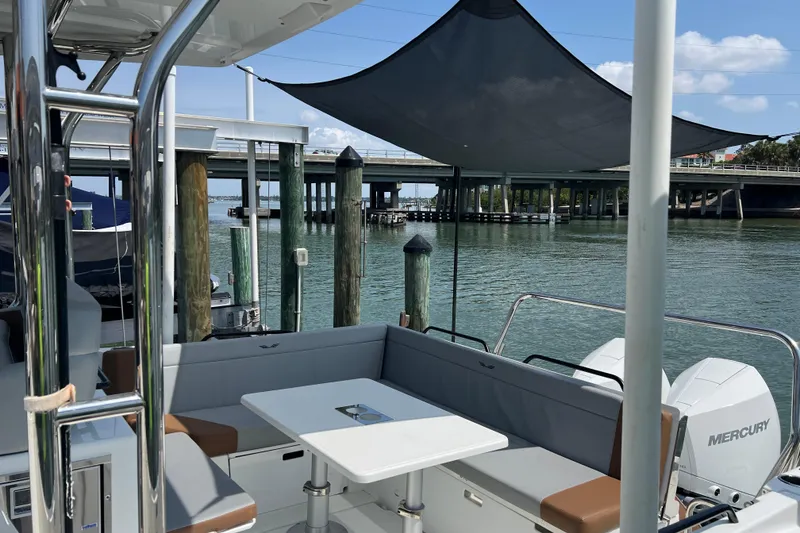 Slide: The Image of 2024 Beneteau Flyer 9 SUNdeck boat interior with seating and table, docked by a bridge. - 10