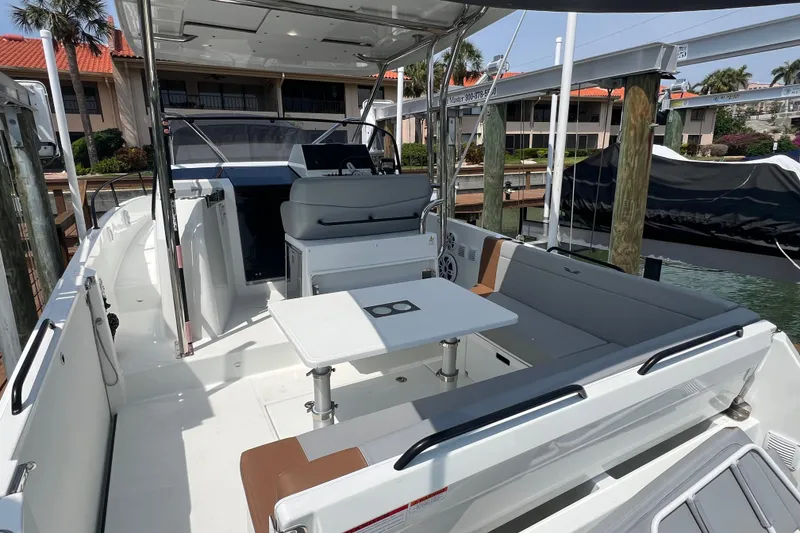 Slide: The Image of 2024 Beneteau Flyer 9 SUNdeck boat interior with seating and table, docked at marina. - 6