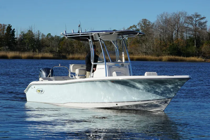 Slide: The Image of 2024 Sea Hunt Ultra 219 boat on calm water, surrounded by trees. - 10