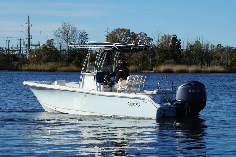 Slide: The Image of 2024 Sea Hunt Ultra 219 boat on calm water with Yamaha outboard motor. - 13