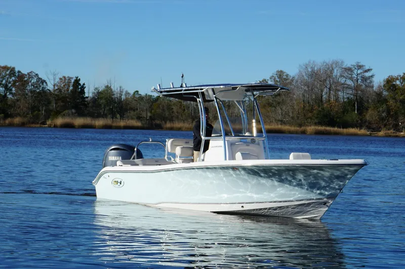 Slide: The Image of 2024 Sea Hunt Ultra 219 boat on calm water with trees in the background. - 16