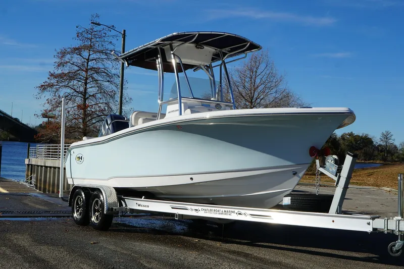 Slide: The Image of 2024 Sea Hunt Ultra 219 boat on trailer by a lakeside ramp. - 19