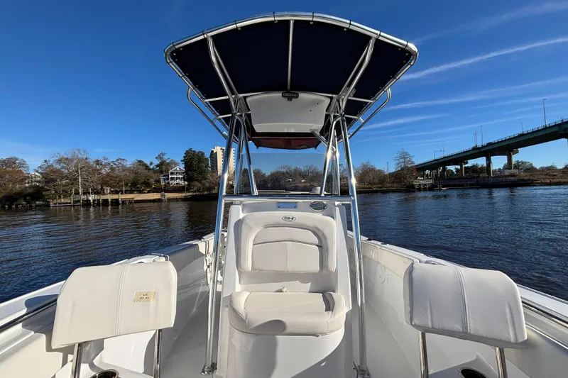 Slide: The Image of 2024 Sea Hunt Ultra 219 boat on a calm river under a clear blue sky. - 4