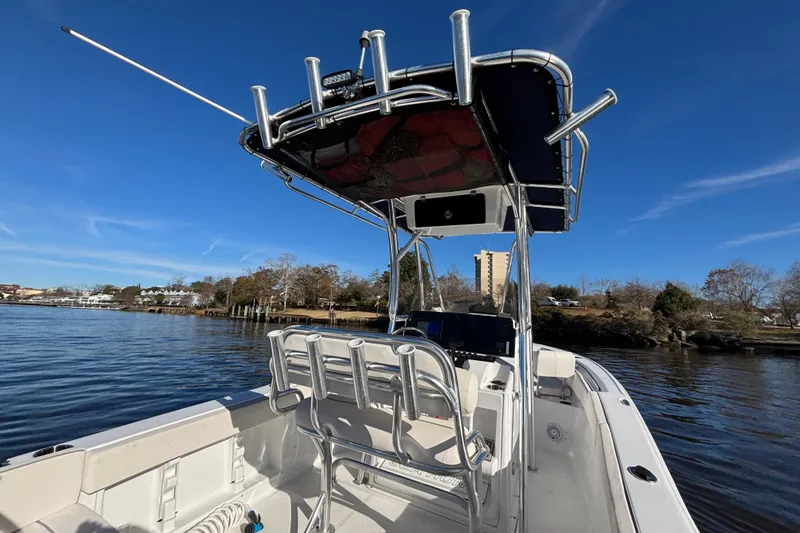 Slide: The Image of 2024 Sea Hunt Ultra 219 boat on calm water under clear blue sky. - 6