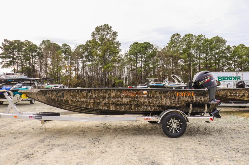Slide: The Image of 2026 Excel Tomahawk boat on trailer, camo design, parked outdoors near trees. - 1