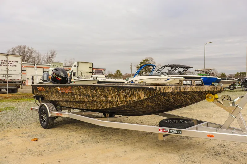 Slide: The Image of 2026 Excel Tomahawk boat on trailer, camo design, parked outdoors. - 6