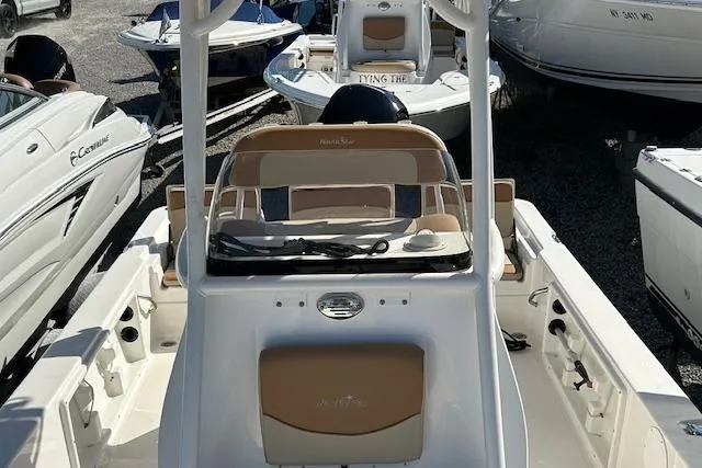 Slide: The Image of 2023 NauticStar 227 XTS boat with tan seating, docked among other boats. - 3
