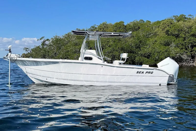 Slide: The Image of 2006 Sea Pro 238 Center Console boat on calm water near lush greenery. - 5