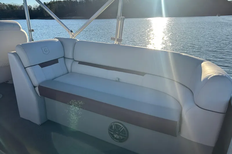 Slide: The Image of 2023 Godfrey Sweetwater 2286 C boat interior with cushioned seating by a sunlit lake. - 19