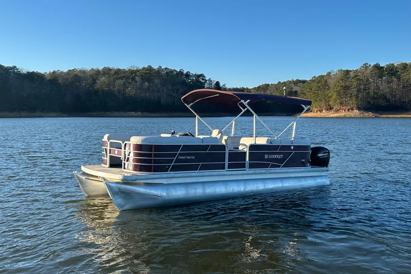 Slide: The Image of 2023 Godfrey Sweetwater 2286 C pontoon boat on a serene lake. - 3