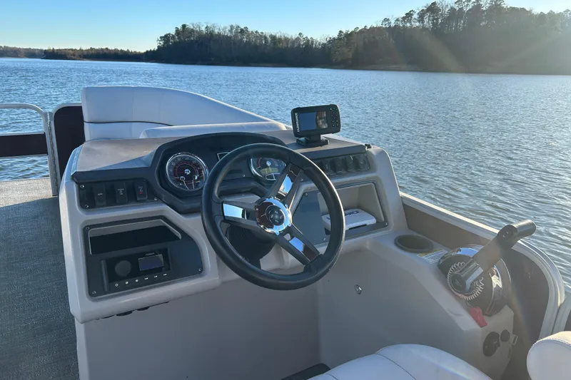Slide: The Image of 2023 Godfrey Sweetwater 2286 C boat dashboard with steering wheel on a serene lake. - 9