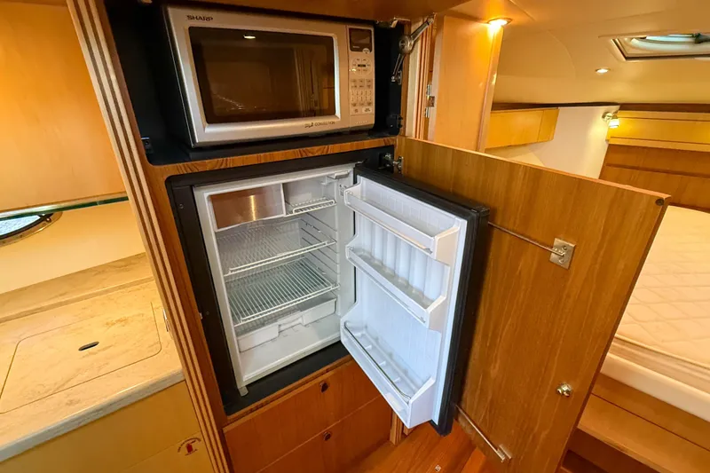 Slide: The Image of 2013 Tiara Yachts 3600 Coronet interior with microwave and open fridge in wooden cabinetry. - 28