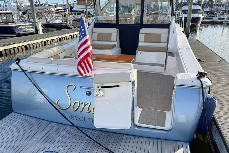Slide: The Image of 2013 Tiara Yachts 3600 Coronet docked, featuring spacious seating and American flag. - 3