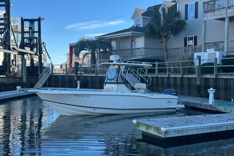 Slide: The Image of 2004 Scout 235 Sportfish boat docked in a marina with waterfront homes. - 1