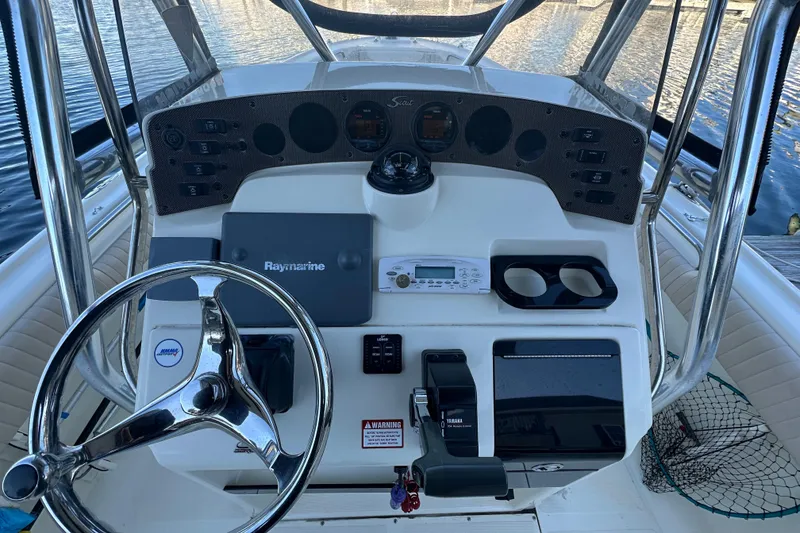 Slide: The Image of 2004 Scout 235 Sportfish boat dashboard with steering wheel and navigation equipment. - 19