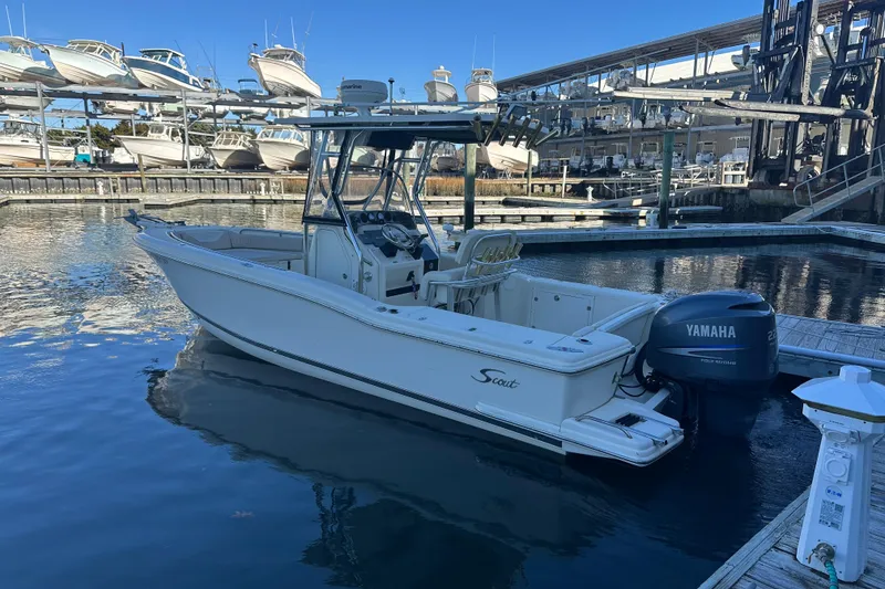 Slide: The Image of 2004 Scout 235 Sportfish boat docked with Yamaha engine, surrounded by marina and other boats. - 2