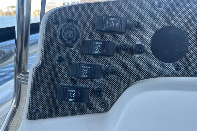 Slide: The Image of Control panel of a 2004 Scout 235 Sportfish boat with various light switches. - 21