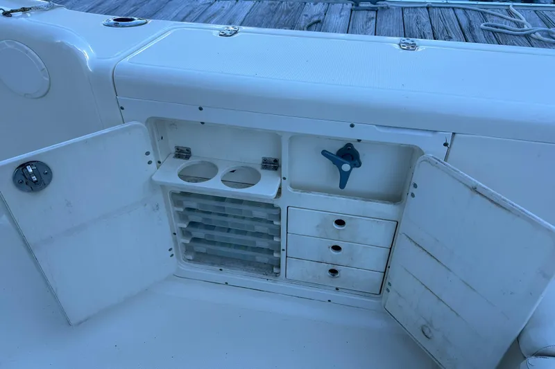 Slide: The Image of 2004 Scout 235 Sportfish boat storage compartment with open doors and tackle drawers. - 30