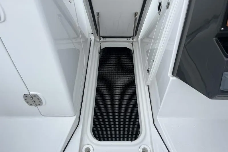 Slide: The Image of 2024 Blackfin 232 DC boat interior with open storage compartment and black mat. - 16