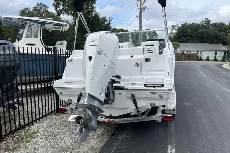 Slide: The Image of 2024 Blackfin 232 DC boat with outboard motor on a trailer, parked near a fence. - 4