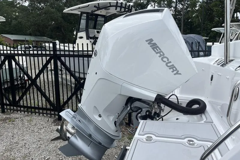 Slide: The Image of 2024 Blackfin 232 DC boat with Mercury outboard engine, parked near a fence. - 5