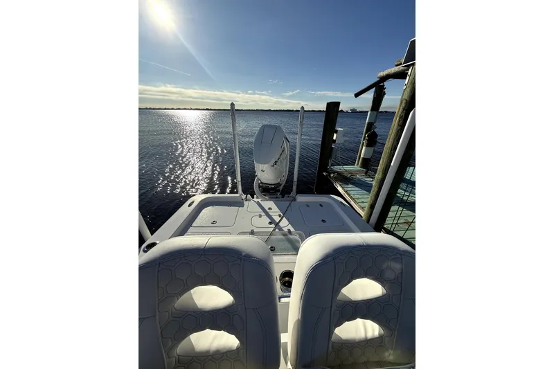 Slide: The Image of 2024 Contender 25 Bay boat interior with dual seats and compass, docked by the water. - 8