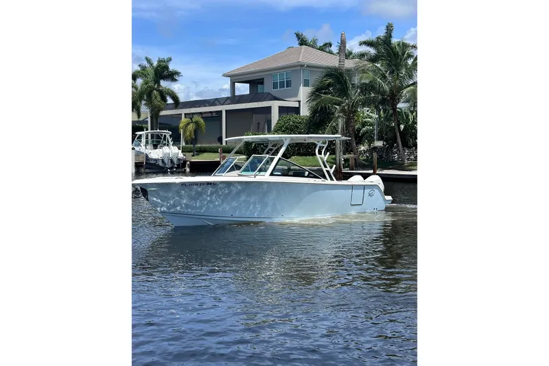 The Image of 2021 Sailfish 276 DC boat cruising on a sunny day near waterfront homes. - 0
