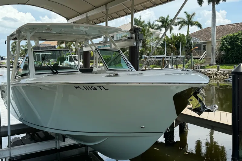 Slide: The Image of 2021 Sailfish 276 DC boat docked under a canopy, surrounded by palm trees. - 3