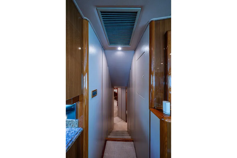 Slide: The Image of Narrow hallway inside 2007 Viking 64 Convertible yacht with wood accents and modern lighting. - 13