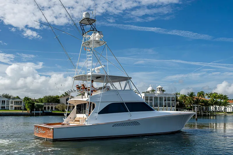 Slide: The Image of 2007 Viking 64 Convertible yacht cruising on a sunny day near waterfront homes. - 6