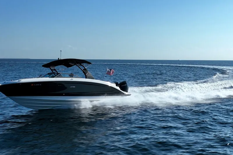 Slide: The Image of 2019 Sea Ray SDX 290 Outboard cruising on open water under clear blue sky. - 52
