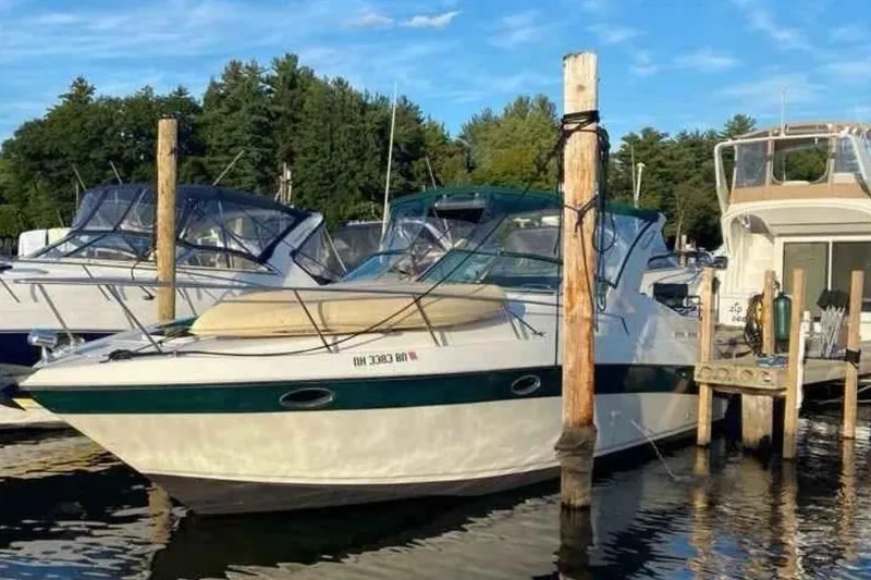 The Image of 1997 Regal Commodore 3260 boat docked at marina, surrounded by other boats, under clear blue sky. - 0