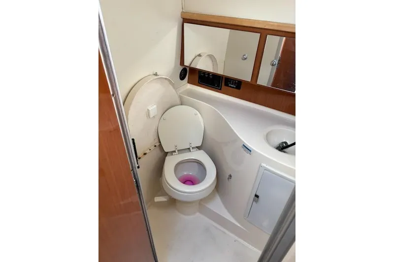 Slide: The Image of 2003 Wellcraft 3300 Coastal boat bathroom with toilet, sink, and mirrored cabinets. - 7