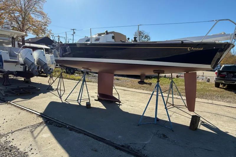 Slide: The Image of 2021 Tartan Fantail sailboat on stands in a boatyard under clear blue sky. - 6