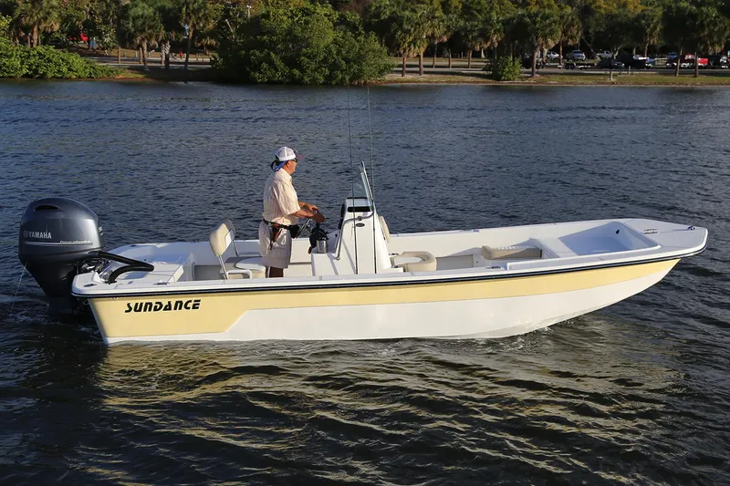 The Image of 2026 Sundance B22CCR boat cruising on a calm river with two passengers. - 0