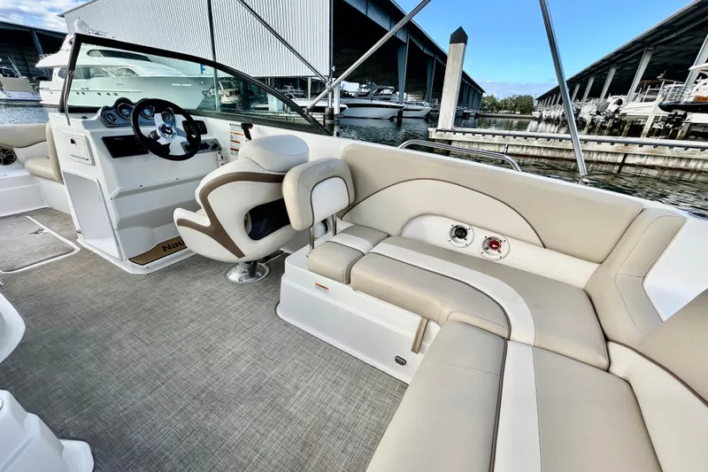 Slide: The Image of 2022 NauticStar 223 DC boat interior with beige seating and steering wheel, docked at marina. - 10