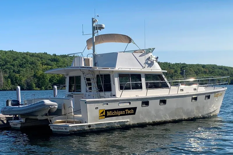 Slide: The Image of Maine Cat P-47 boat from 2009 docked on a scenic lake with lush greenery. - 2