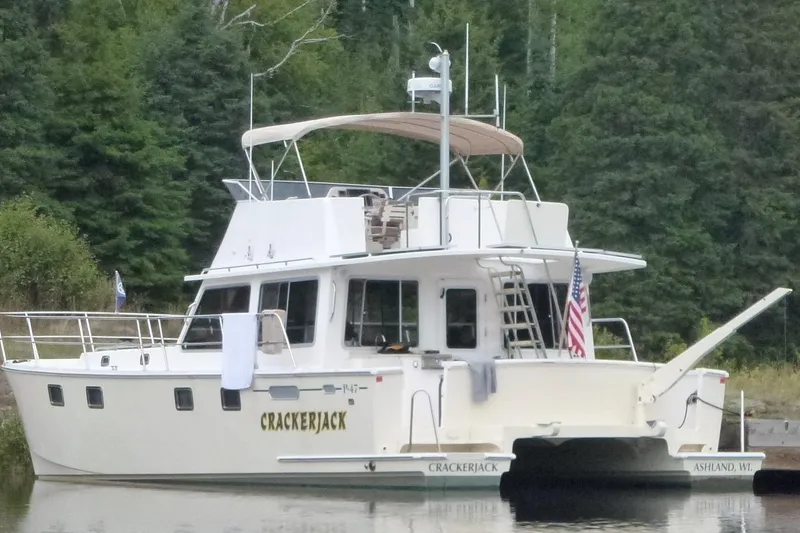Slide: The Image of Maine Cat P-47 boat named Crackerjack docked by forested shoreline, 2009 model. - 3