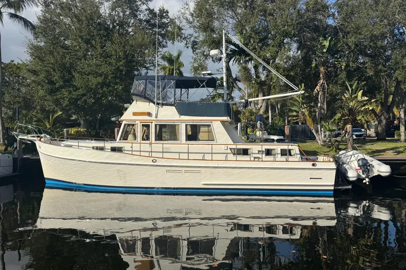 The Image of 1990 Grand Banks 46 Classic yacht on calm water, surrounded by lush greenery. - 0