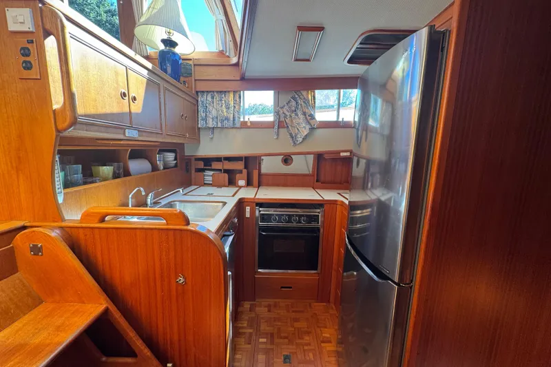 Slide: The Image of 1990 Grand Banks 46 Classic yacht interior with wooden cabinetry and kitchen amenities. - 23