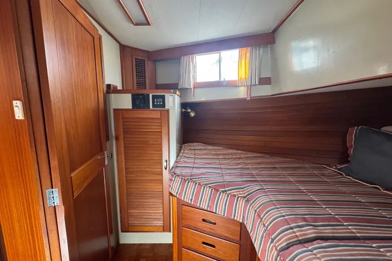 Slide: The Image of Cozy cabin interior of 1990 Grand Banks 46 Classic with striped bedding and wooden cabinetry. - 31