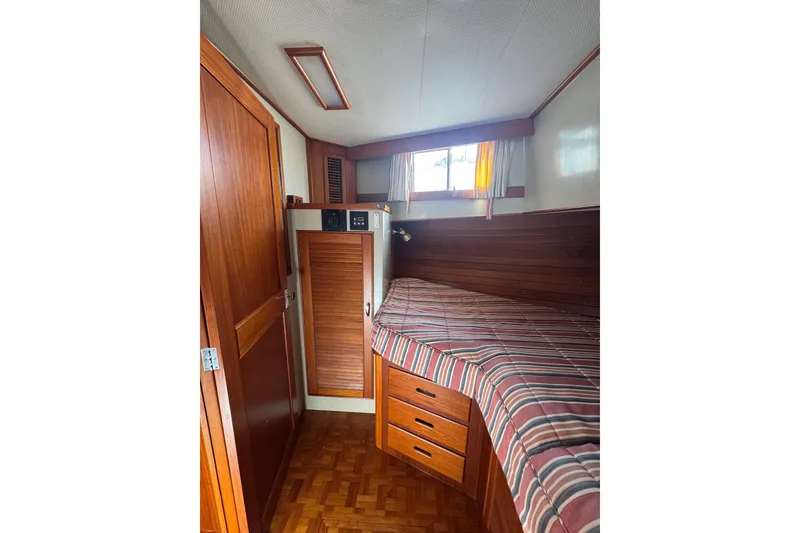 Slide: The Image of Cozy cabin interior of 1990 Grand Banks 46 Classic yacht with wood paneling and striped bedding. - 32