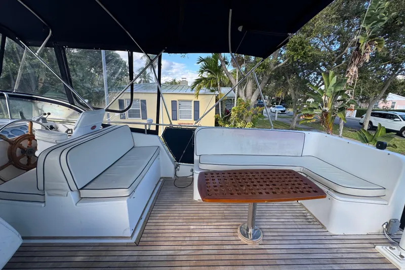 Slide: The Image of Deck view of 1990 Grand Banks 46 Classic yacht, featuring seating and table, docked by a canal. - 53