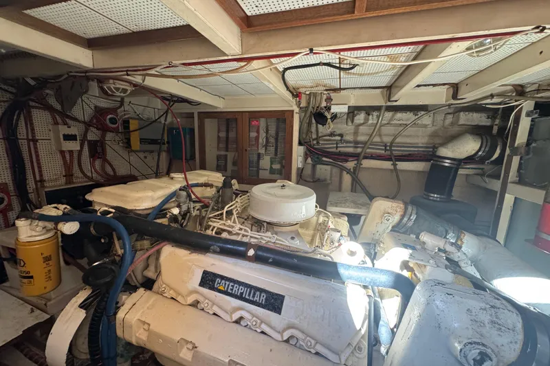 Slide: The Image of Engine room of a 1990 Grand Banks 46 Classic yacht, featuring machinery and fire extinguisher. - 60