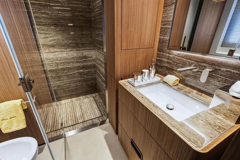 Slide: The Image of Luxurious bathroom with wood accents, marble sink, and glass shower in a 2018 Custom Line 120 yacht. - 108